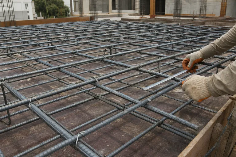 Tied slab reinforcement grid being checked before concrete placement